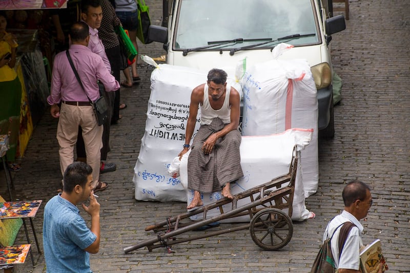 A man rests on a bundle, July 20, 2016 at Yangon Market, Yangon, Myanmar. (Alex Berger via Flickr)