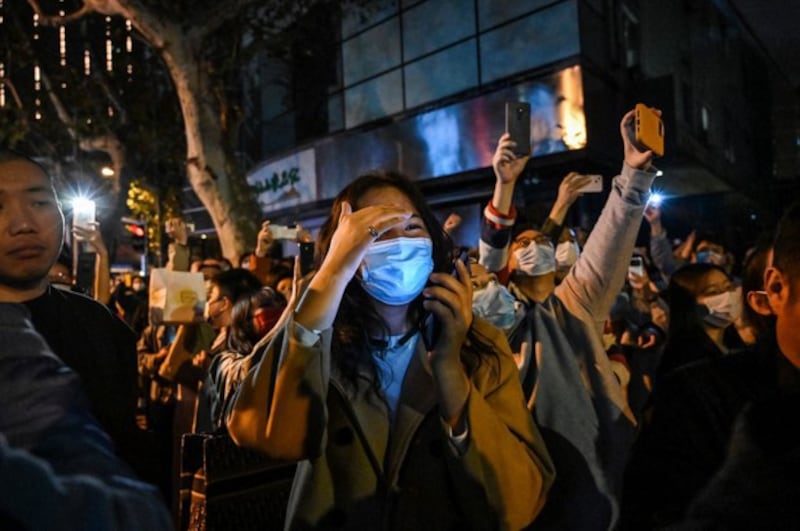 People gather on a street in Shanghai on November 27, 2022, where protests against China's zero-Covid policy took place the night before following a deadly fire in Urumqi, the capital of the Xinjiang region. (Photo by Hector RETAMAL / AFP)
