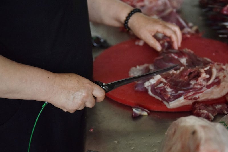 خوتەندىكى ئۇيغۇر رېستورانىدا ئاشپەزنىڭ ئېشىلگەن سىم بىلەن باغلاپ قويۇلغان پىچاقنى ئىشلىتىۋاتقان كۆرۈنۈشى. 2019-يىلى 31-ماي.