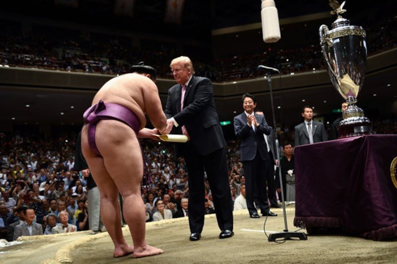 特朗普穿皮鞋进“土俵”颁发奖杯,打破不得穿鞋进入“土俵”的相扑传统。安倍如此安排被视为将有大改革。“土俵”是相扑力士竞技的圆圈,非常神圣。(AFP)